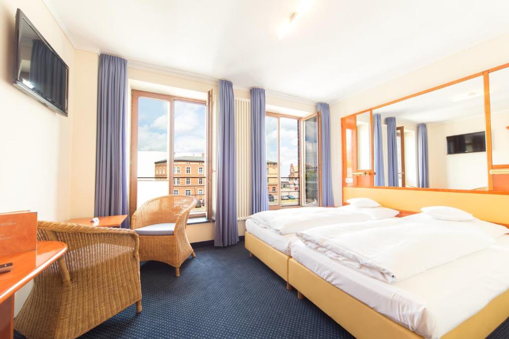 Hotel Kontorhaus Stralsund في شترالزوند: غرفة في الفندق بها سرير ومكتب ونوافذ