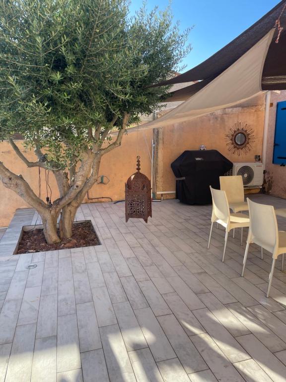 une tente avec un arbre, des chaises et une table dans l'établissement le beal, à Hyères