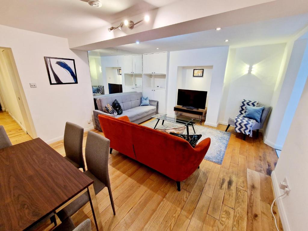 a living room with a red couch and a table at Beautiful Hyde Park Flat by Lancaster Gate Station with Private Back Patio in London
