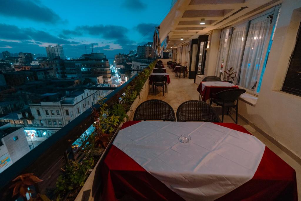 balcón con mesas y sillas y vistas a la ciudad en Borg El Thaghr Hotel en Alexandría