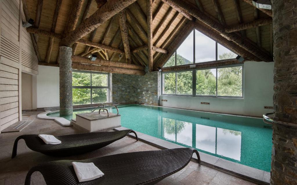 - une grande piscine avec des chaises dans un bâtiment dans l'établissement Lagrange Vacances L'Ardoisière, à Saint-Lary-Soulan