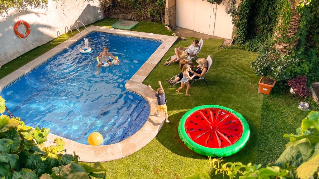 a group of people sitting around a pool with a watermelon at Villa del Jerte in El Torno