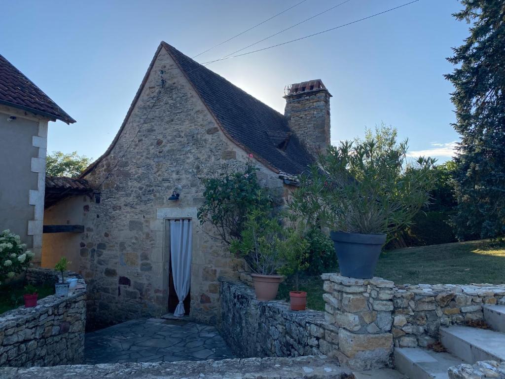 una antigua casa de piedra con un muro de piedra en L’Hirondelle, en Castelnaud La Chapelle