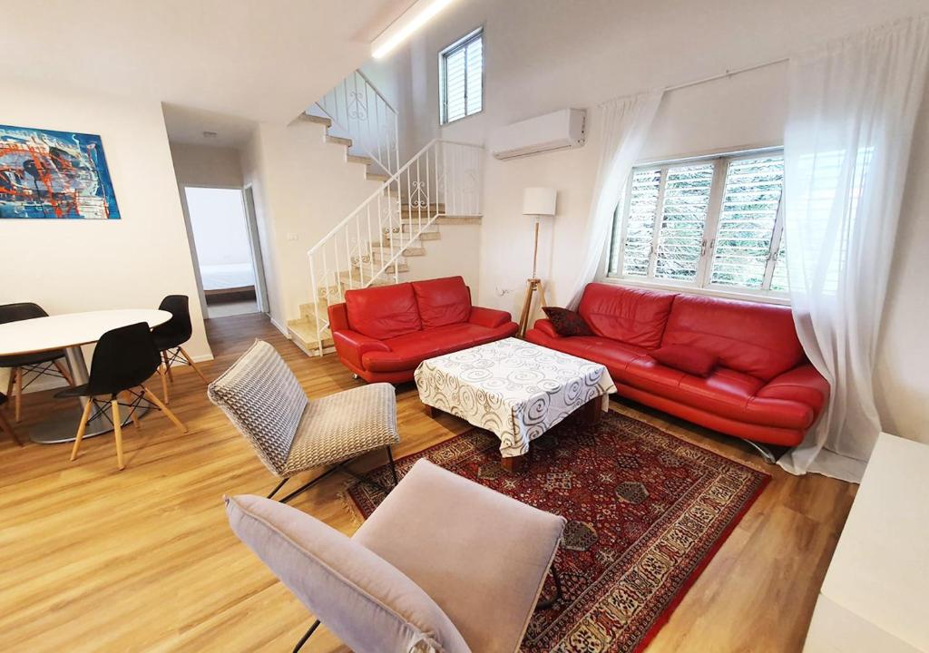 a living room with a red couch and a table at Spacious 3BD Penthouse with Rooftop & Parking in Ra‘ananna