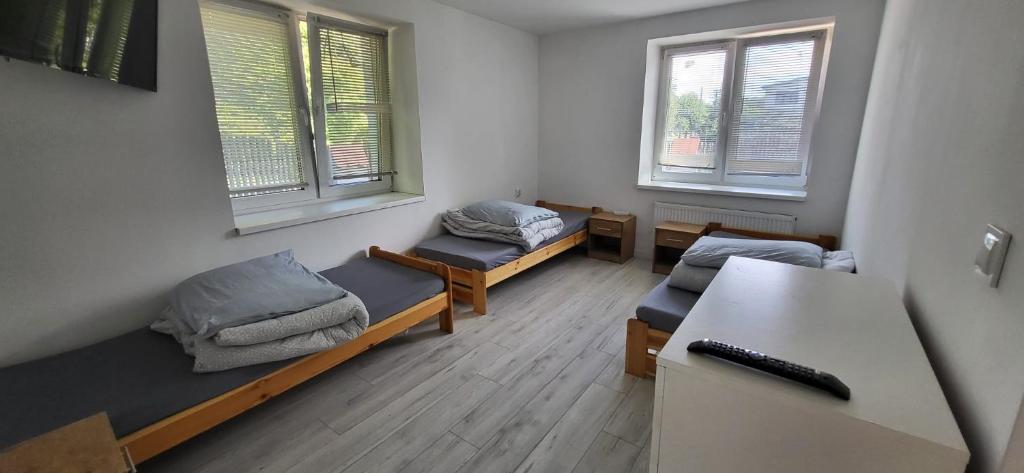 Habitación con 2 camas, escritorio y 2 ventanas. en Noclegi Tuszyn, en Tuszyn