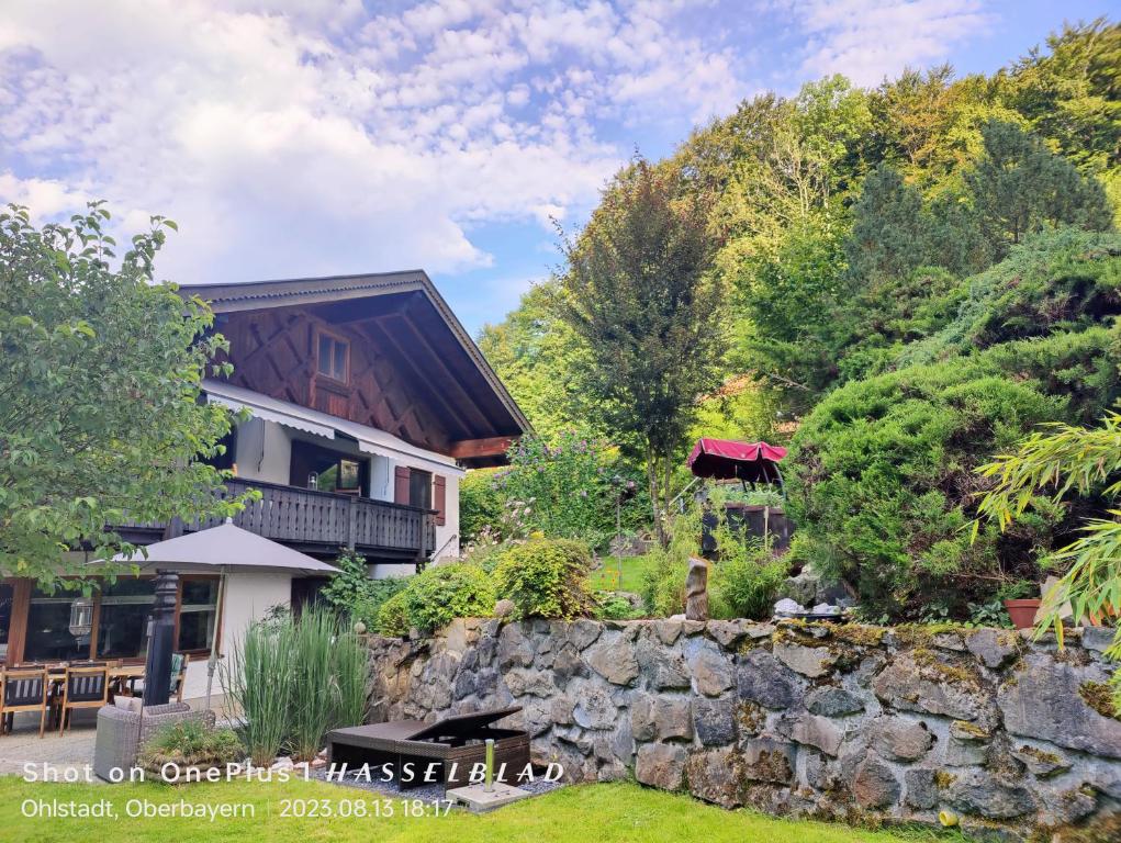 ein Haus mit einer Steinmauer vor einem Hof in der Unterkunft Ferienapartment Opitz - Zugspitzregion in Ohlstadt