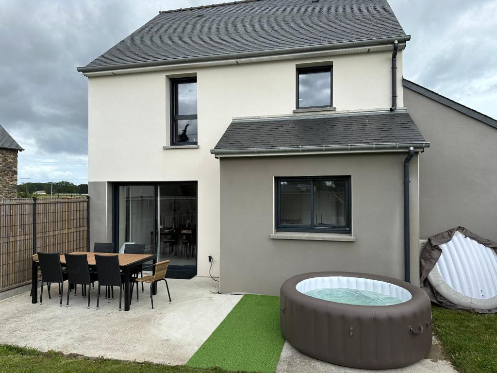 une maison avec une table et des chaises dans la cour dans l'établissement Maison avec Jacuzzi 1-8 pers à 10 mn de st Malo, à Saint-Méloir-des-Ondes