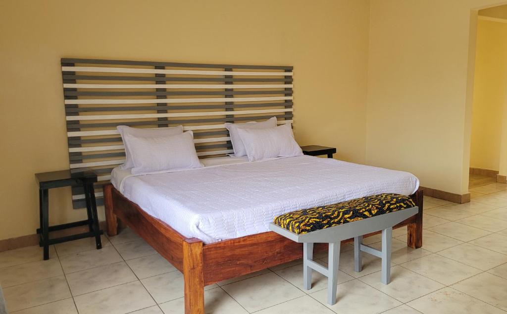 a bed in a room with two pillows and a chair at Quest in Lilongwe