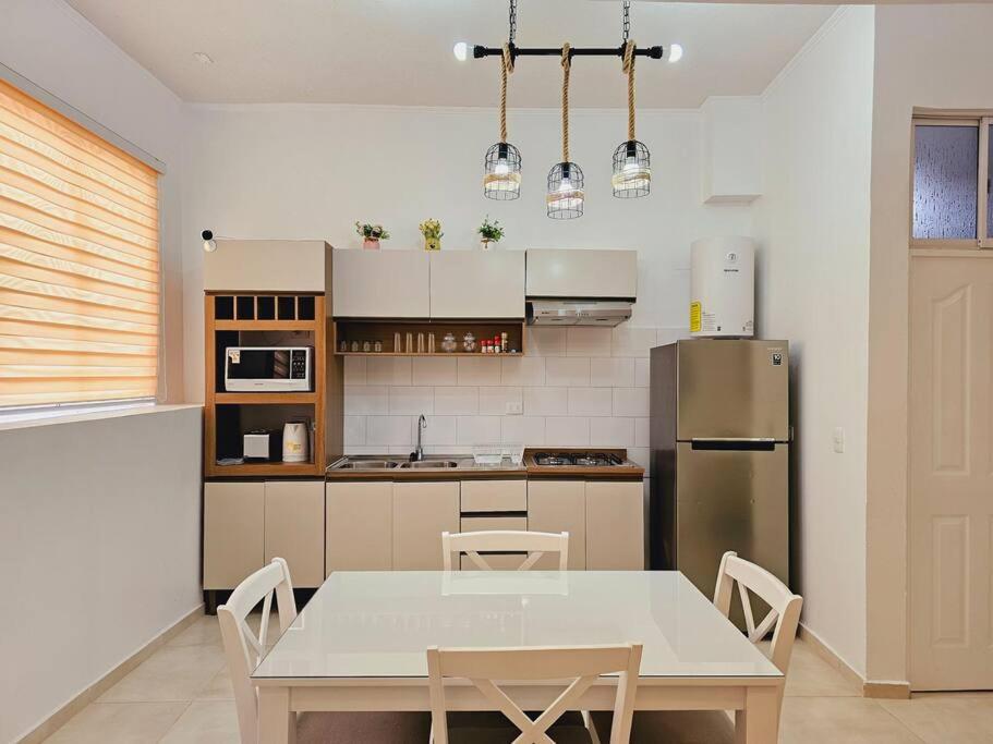 a kitchen with a table and chairs and a refrigerator at Exclusivo Dpto 101 con Terraza en Antofagasta in Antofagasta