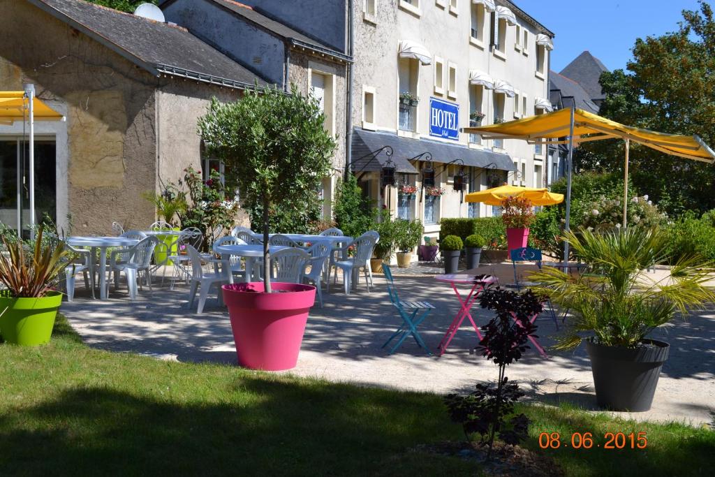a patio with tables and chairs and potted plants at Hôtel Le Castel in Brissac-Quincé