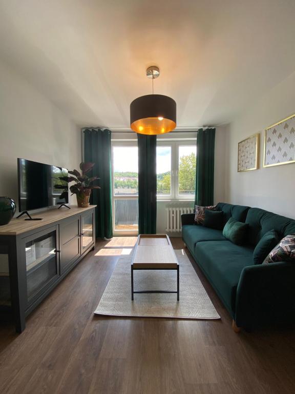 a living room with a green couch and a table at Apartament Słowackiego 29 in Gdańsk