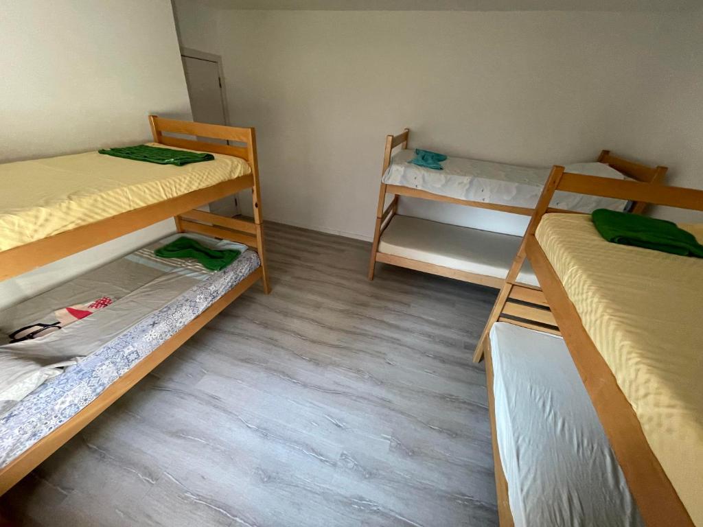 a room with three bunk beds and a wooden floor at Rock Hostel in Pristina