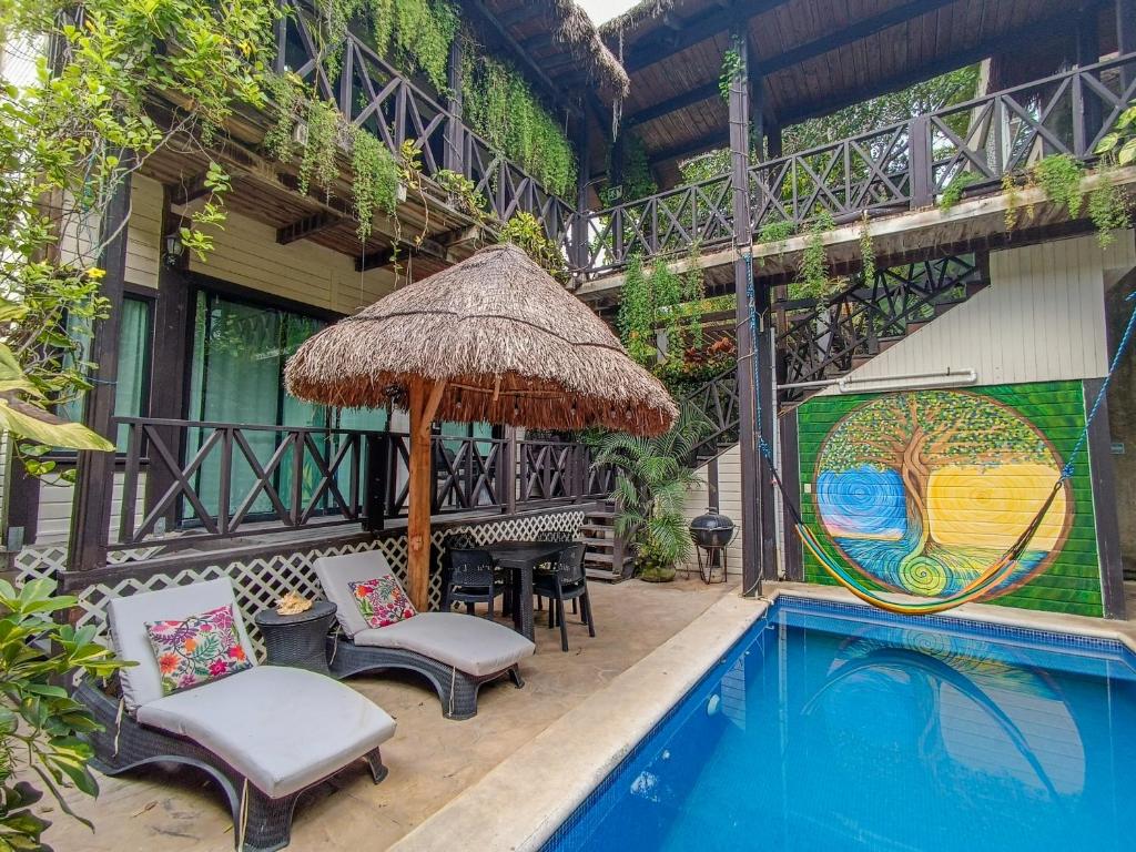 patio z krzesłami i parasolem przy basenie w obiekcie Alicat Villas w mieście Tulum