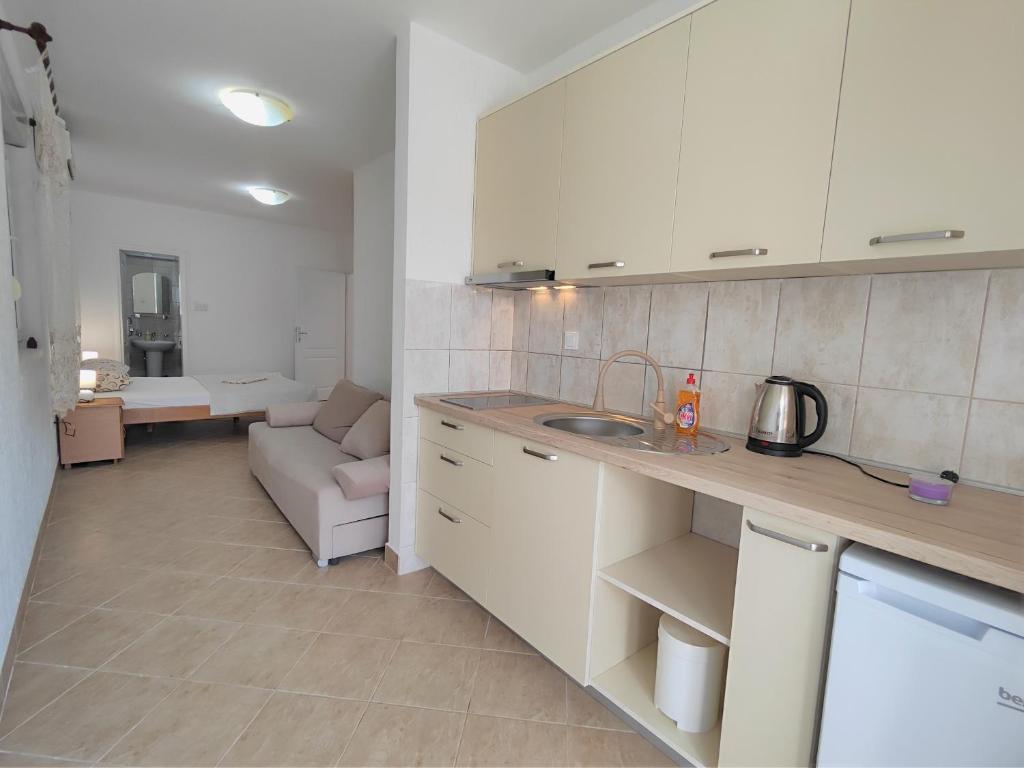 a kitchen with white cabinets and a couch in a room at MM Apartments in Budva