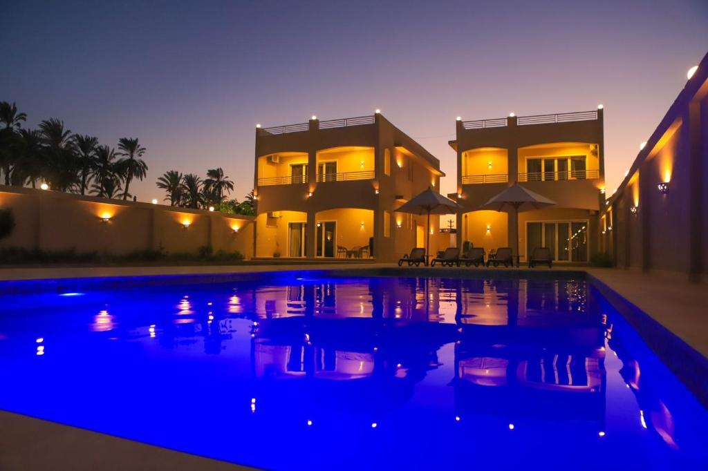 a large house with a swimming pool at night at Royal Nile Villas - Pool View Apartment 2 in Luxor