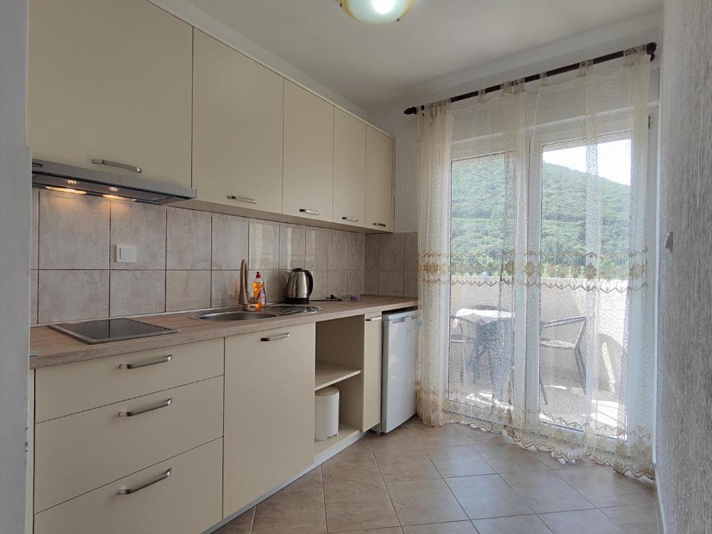 a kitchen with white cabinets and a large window at MM Apartments in Budva