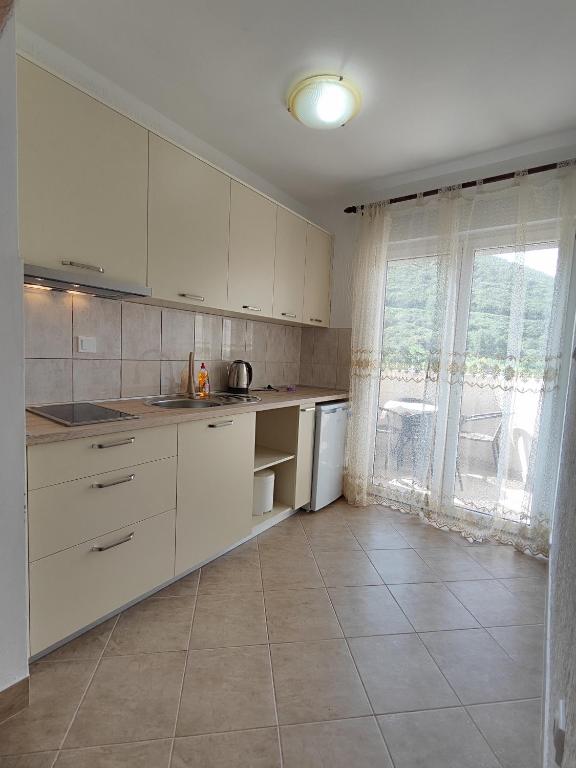 a kitchen with white cabinets and a large window at MM Apartments in Budva