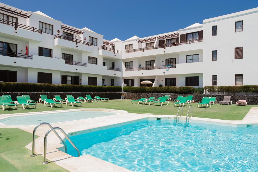 een hotel met een zwembad en stoelen en een gebouw bij Tyler's House Ocean View in Costa Teguise