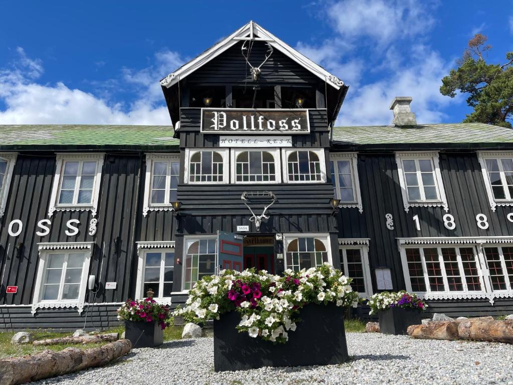 ein schwarzes Gebäude mit Blumen davor in der Unterkunft Pollfoss Hotell in Skjåk
