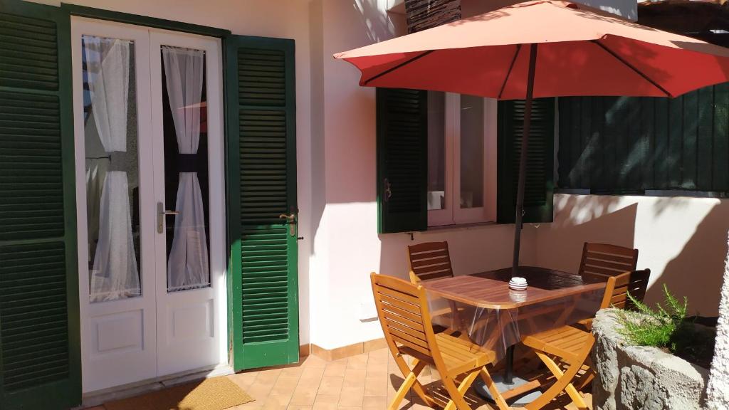 a wooden table with a red umbrella on a patio at Casetta Emilia vicino al mare in Ischia