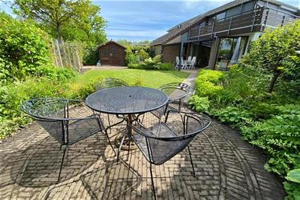 a patio with a table and chairs and a house at De Vlinder in Brouwershaven