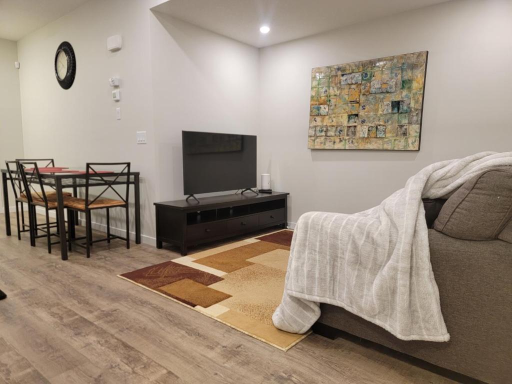 sala de estar con sofá, TV y mesa en 2-Bedroom Guest Suite en Calgary