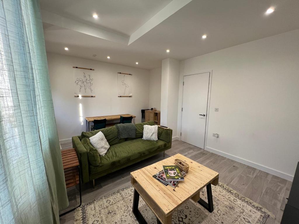 a living room with a green couch and a table at Lovely 1-bedroom flat with Patio in London
