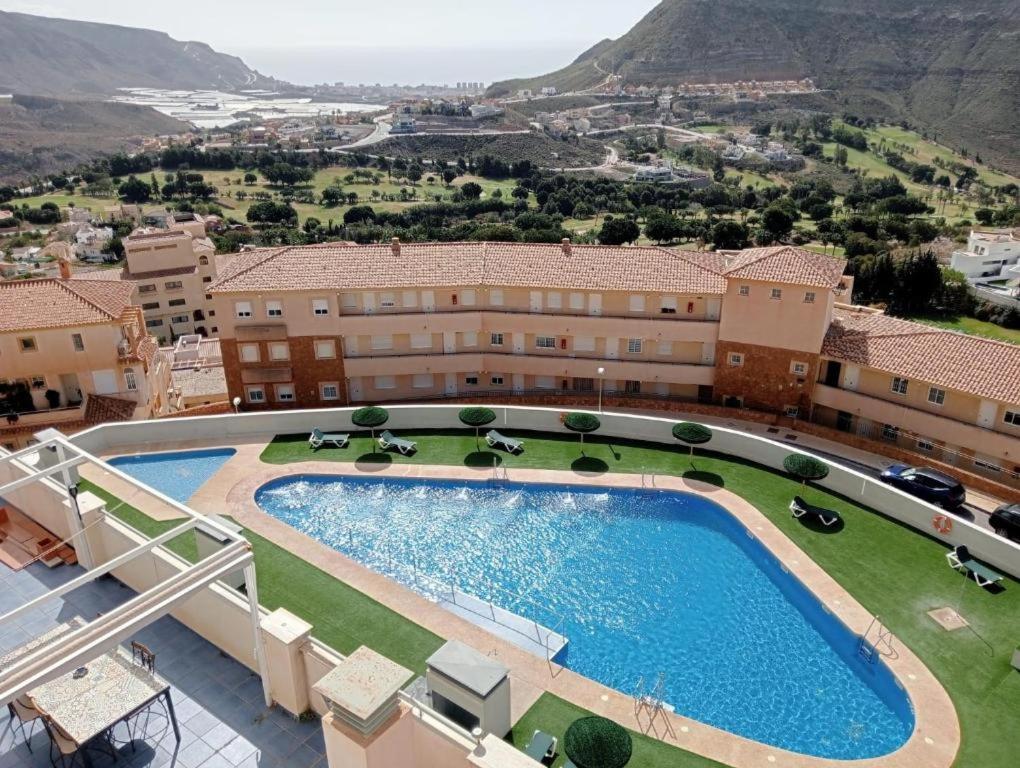 a resort with a large swimming pool and mountains in the background at Golf, piscina climatizada y playa in La Envia