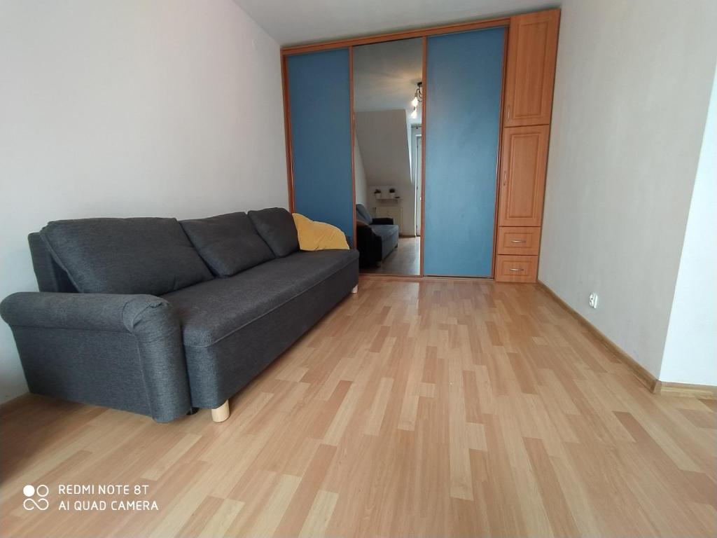 sala de estar con sofá y suelo de madera en Kawalerka na Ślichowicach en Kielce
