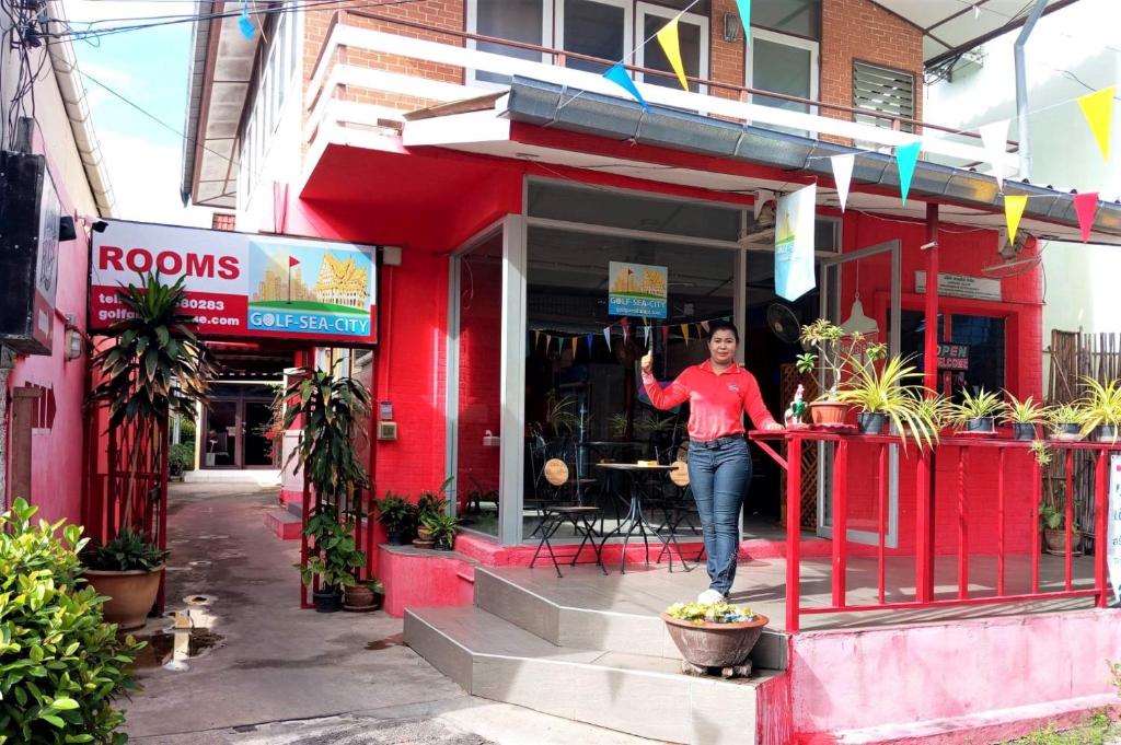 a woman standing in front of a red building at Taphouse in Hua Hin