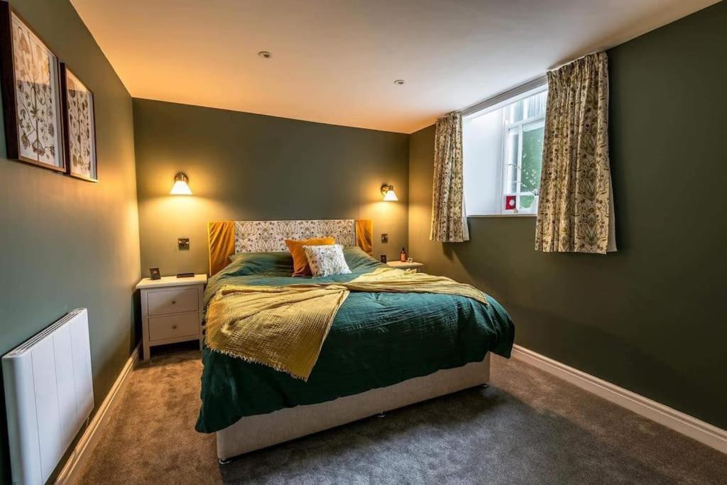 een slaapkamer met een bed met groene muren en een raam bij Converted Welsh Sunday School with Sea View & Garden on Anglesey - Dog Friendly in Amlwch
