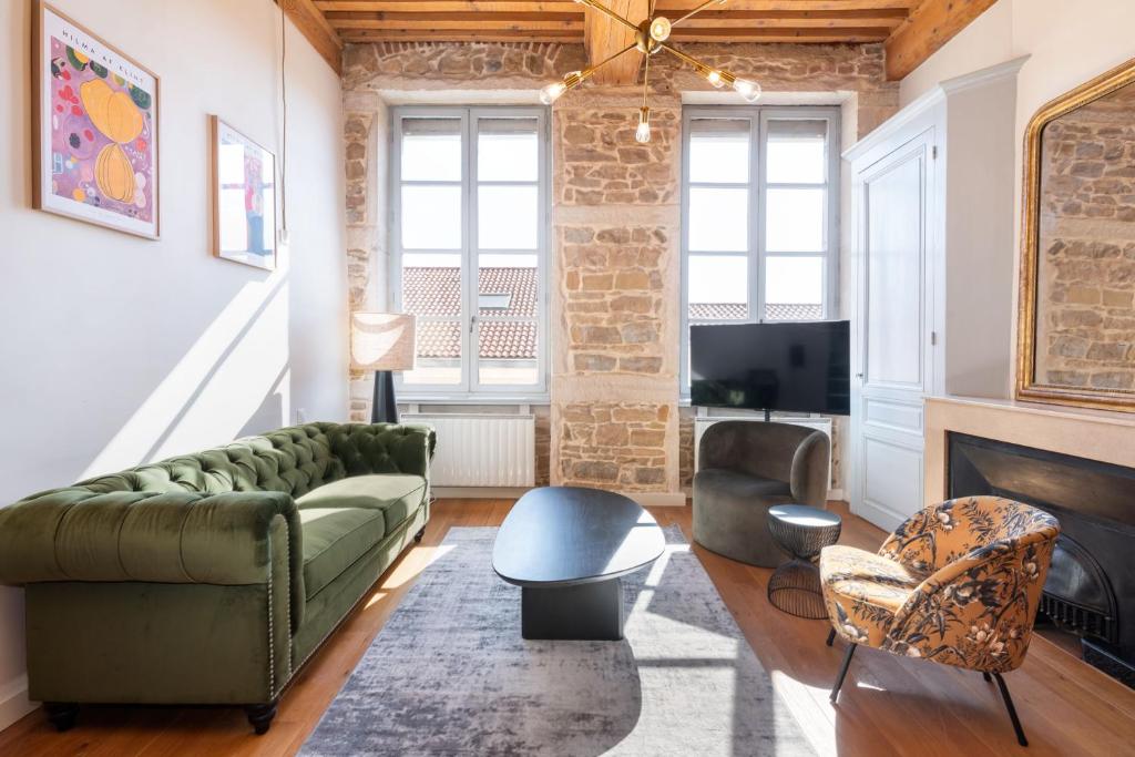 Le Cocon Pacôme Les Autres في ليون: غرفة معيشة مع أريكة خضراء ومدفأة
