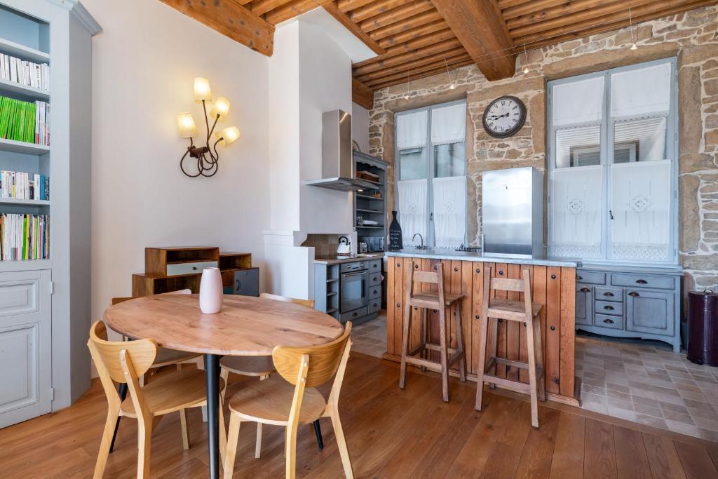 a kitchen with a table and chairs and a clock on the wall at Le Cocon Pacôme Les Autres in Lyon