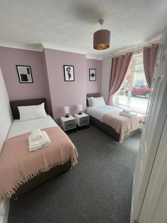 Duas camas num quarto com paredes cor-de-rosa em Seaside Paradise em Lowestoft