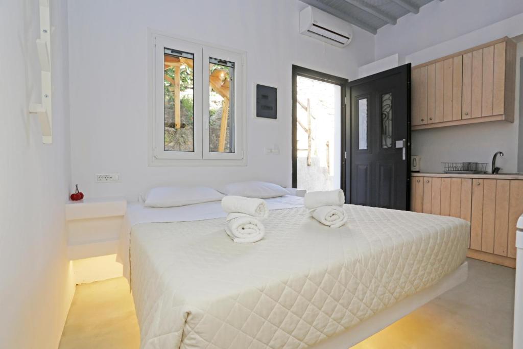 a white bedroom with two beds and a kitchen at Brand New Mykonos Town Suites in Mikonos