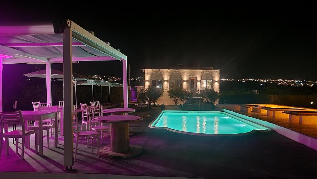 una piscina con mesas y sillas por la noche en Mare Nostrum Santo, en Oia