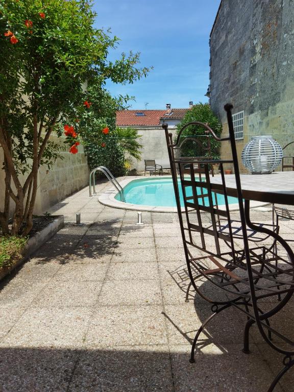 une chaise à côté d'une table et d'une piscine dans l'établissement La maison margalaise, à Margaux