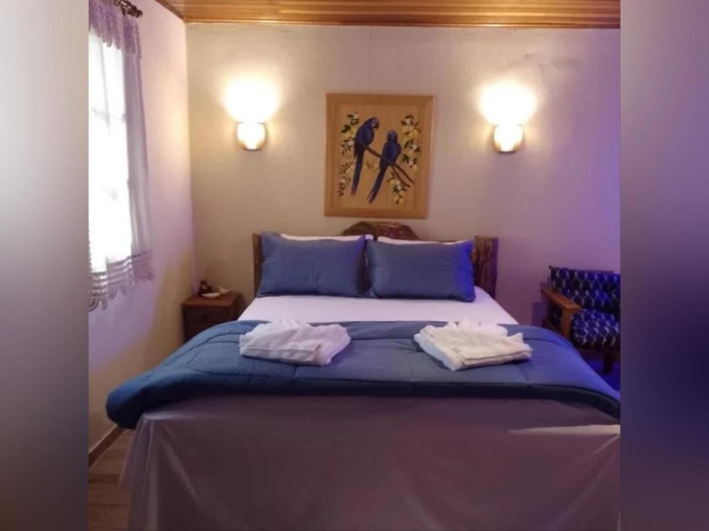 a bedroom with a blue bed with towels on it at Pousada recanto Lajinha maua in Resende