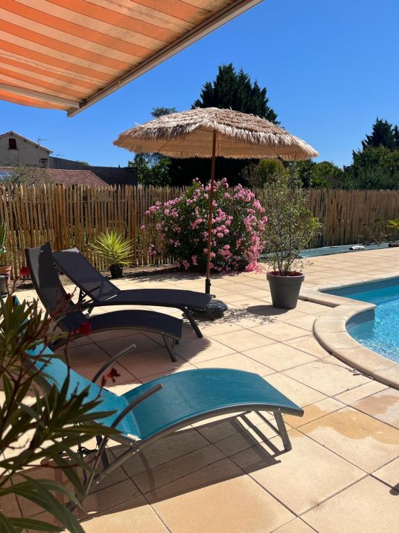 un patio con 2 sillas, una sombrilla y una piscina en Les voyages de Louison, en Lavardac