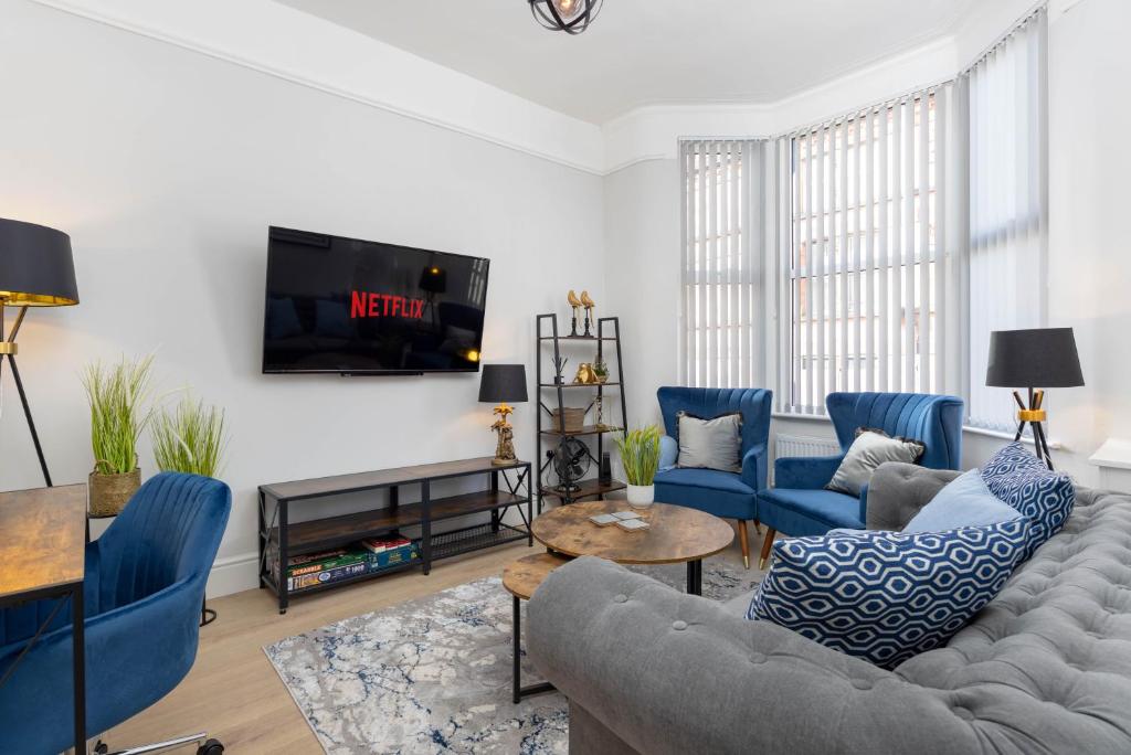 a living room with blue chairs and a tv at Stylish & modern home across the road from the famous Penny Lane walking distance to cafes restaurants and supermarkets in Liverpool