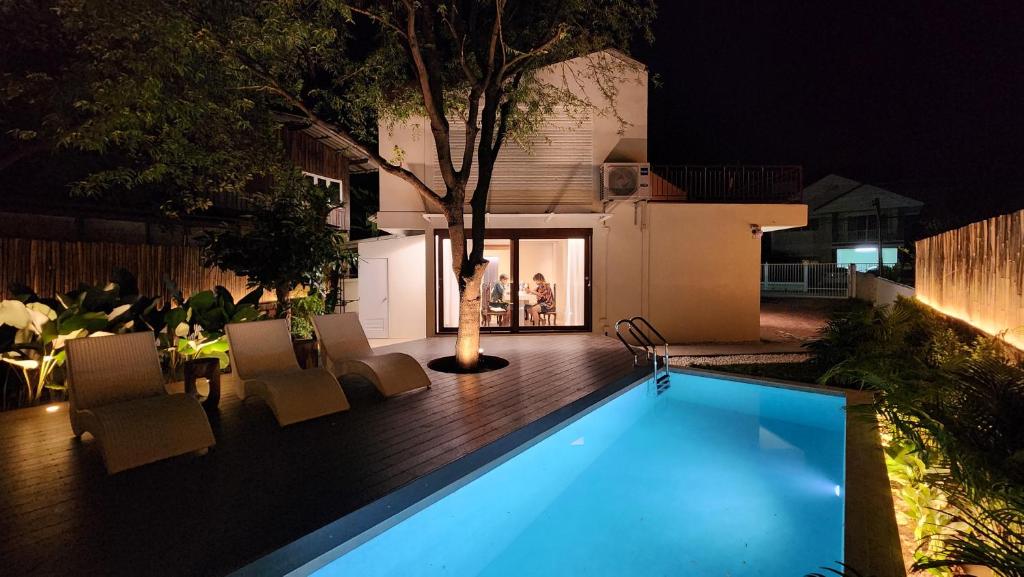 Una piscina en un patio trasero por la noche. en Sense of Haiya, en Chiang Mai