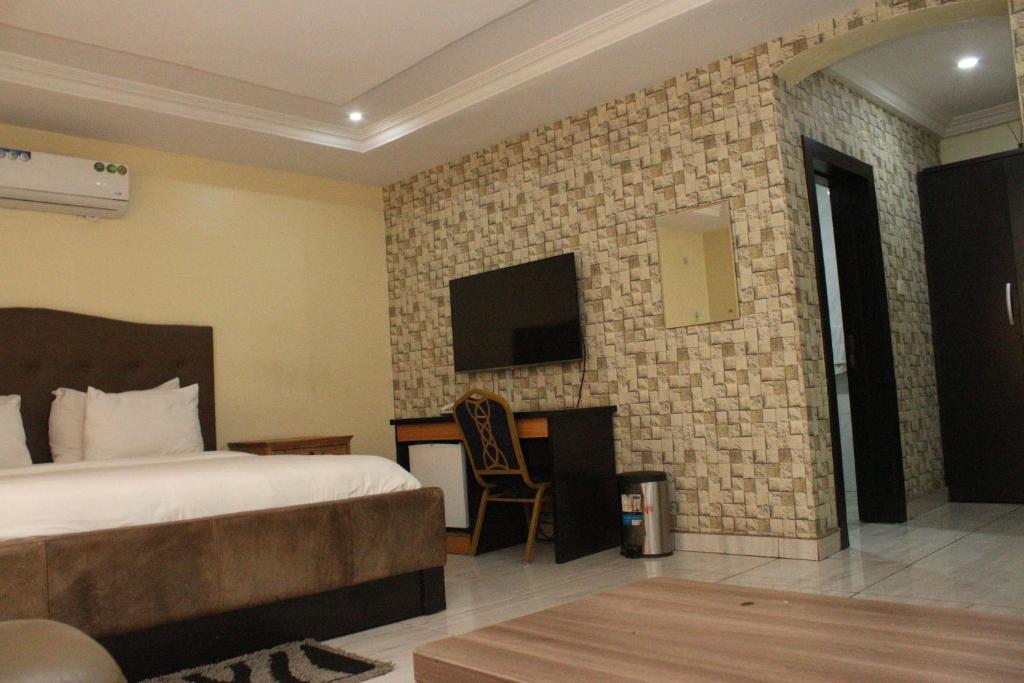 a hotel room with a bed and a tv on a wall at MITOS LUXURY SUITES (ANNEX) in Lagos