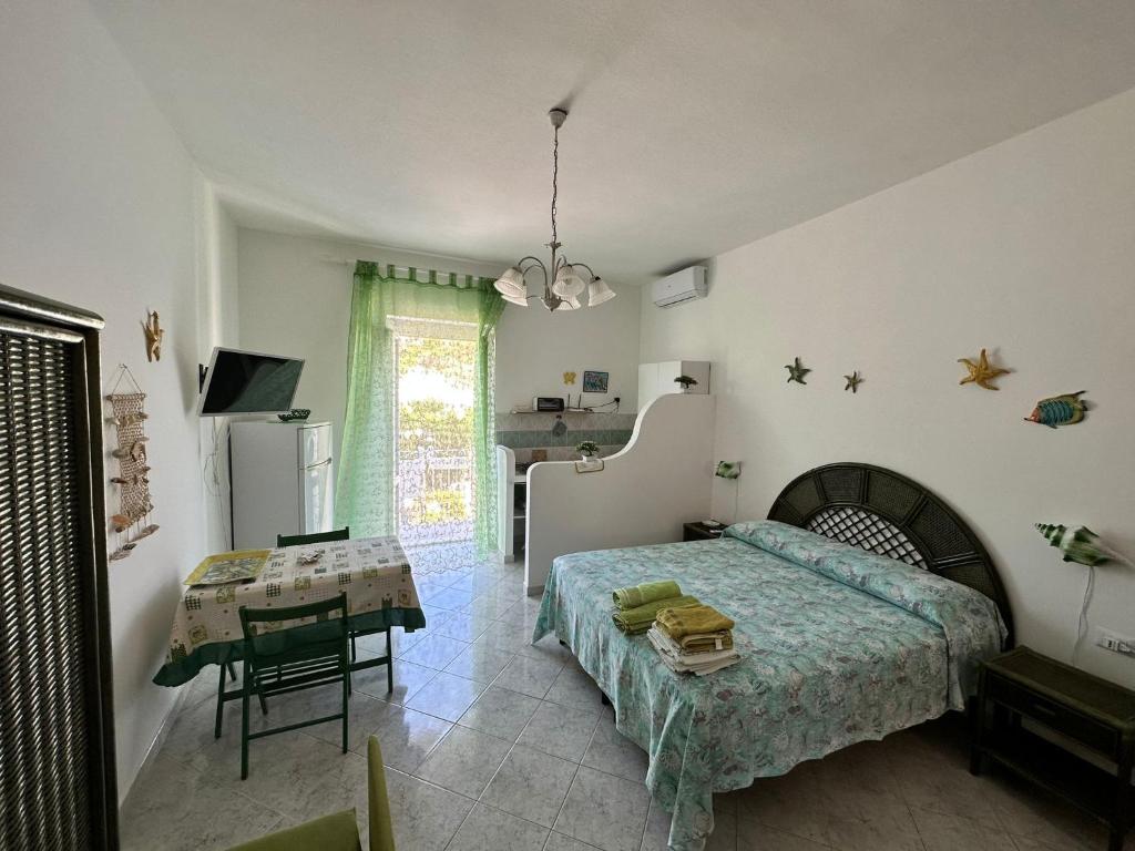 ポンツァにあるIl monolocale verde conchiglie e fioriのベッドルーム(ベッド1台、テーブル付)