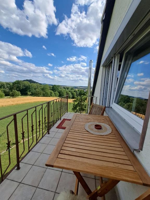 a wooden table on a balcony with a view of a field at Ferienwohnung mit Weitblick in Nordhessen in Gudensberg