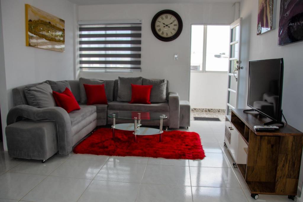 a living room with a couch and a red rug at Apartamentos amoblados Margaritas in Ríohacha