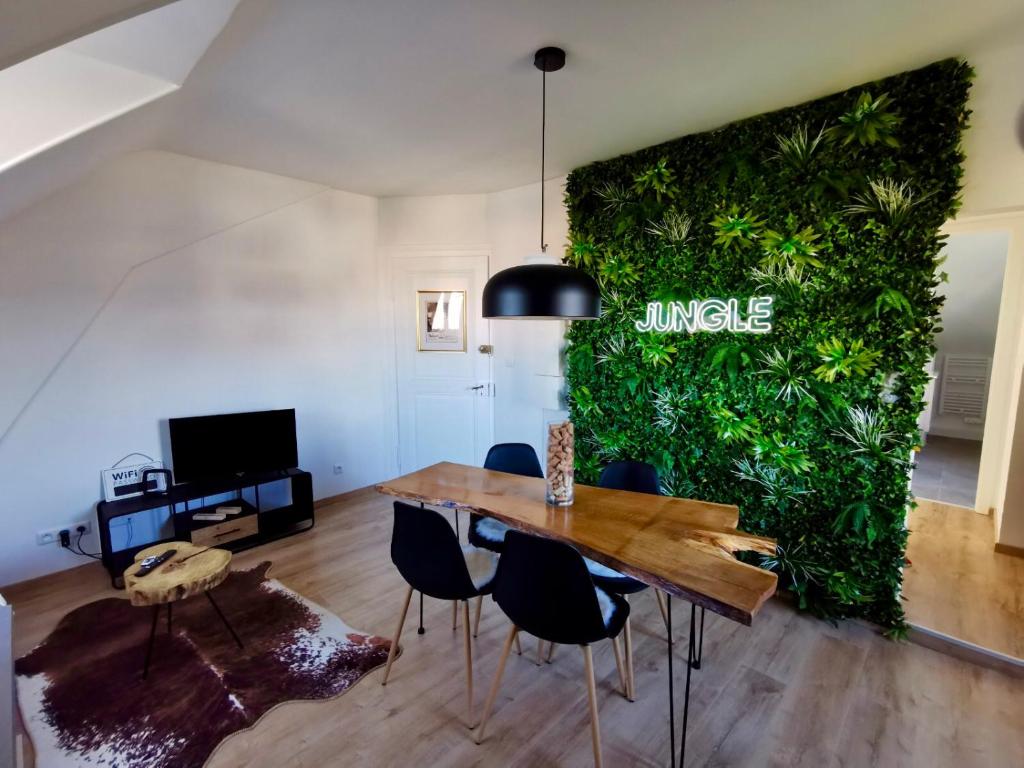 a dining room with a large green wall at ÉVASION JUNGLE - Wifi & Netflix ! in Mulhouse