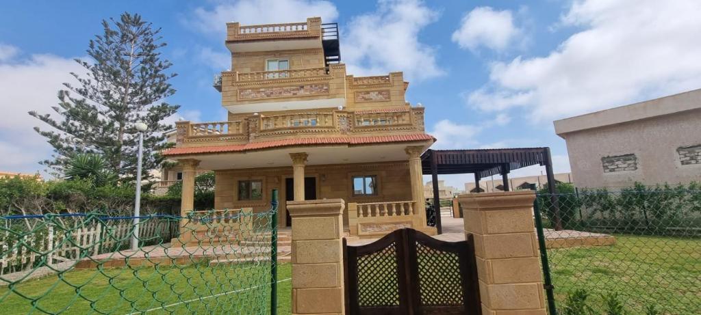 uma casa com uma torre no topo de uma cerca em شاليه فندقي بقرية بدر بالساحل الشمالي em El Alamein