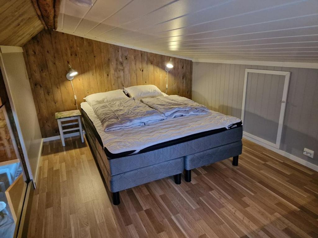 ein Schlafzimmer mit einem Bett in einem Zimmer mit Holzwänden in der Unterkunft Autentisk rorbu in Moskenes