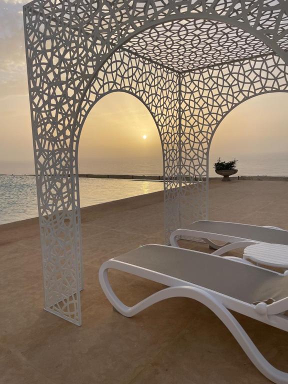 a white bed on the beach with the sunset at Villa La Falaise in Oualidia