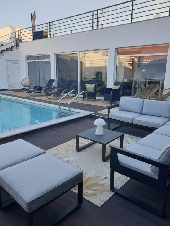 a swimming pool with couches and tables next to a swimming pool at Casa das Almoleias in Castro Verde